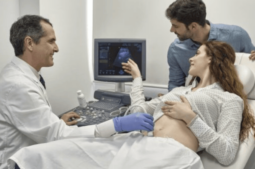 A woman getting a scan with a doctor and partner.